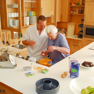 Bild eines Pflegers und einer Bewohnerin beim Kuchen backen.